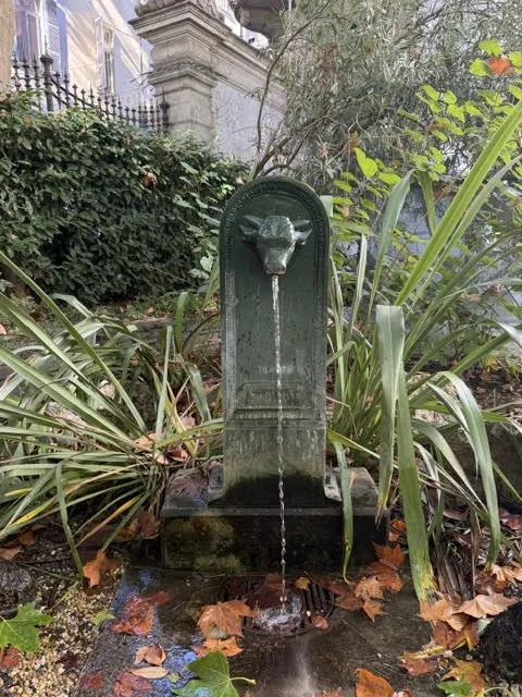 Un toret, la tipica fontanella verde con la testa di toro, in un giardino di Torino